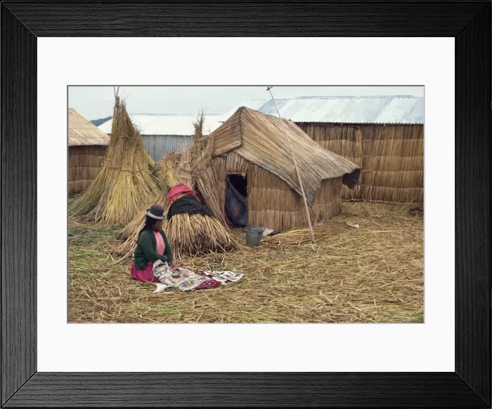 Framed Print : A woman with her sewing sitting outside her reed house