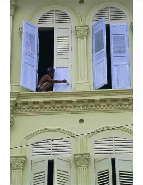 Man painting shutters on a house