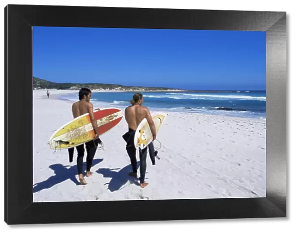 Two surfers walking with their boards on Kommetjie beach