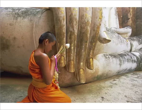 Novice Buddhist monk and Phra Atchana Buddha statue