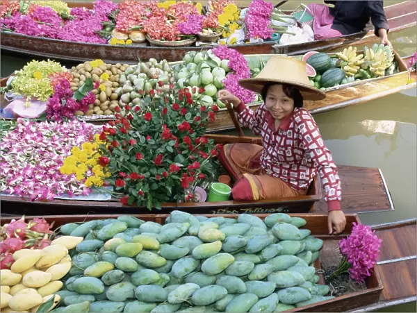 Market trader in boat selling flowers and fruit