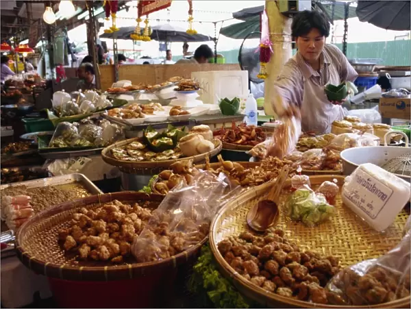 A shopkeeper puts fish cakes on a tray on a stall in