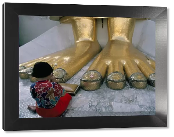 Woman praying at the feet of the Buddha in the temple