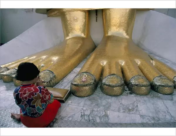 Woman praying at the feet of the Buddha in the temple