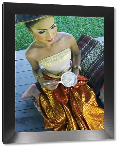 Girl in traditional Thai clothes eating rice