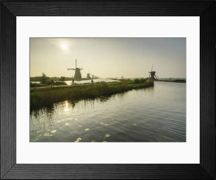 Framed Print : Bicycles run through a path between the canal and windmills, Kinderdijk, Rotterdam