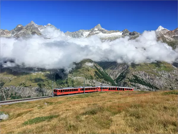 The Bahn train on its route with high peaks and mountain range in the background