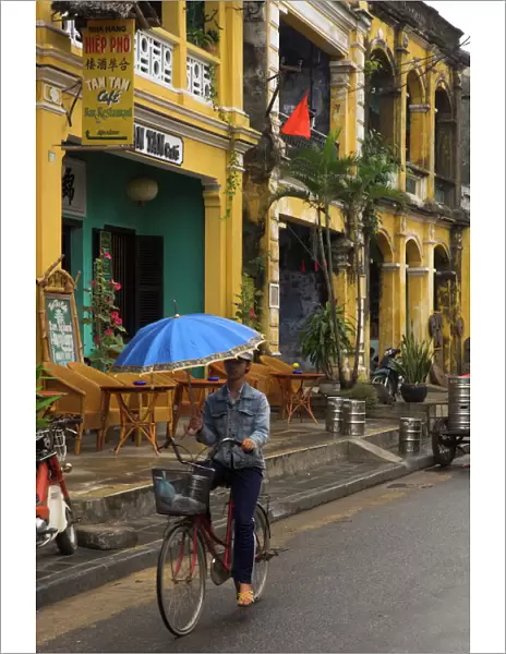 Man riding a bike and holding umbrella