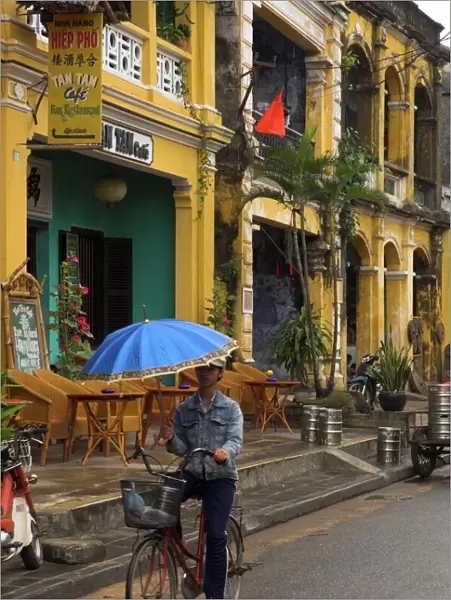 Man riding a bike and holding umbrella
