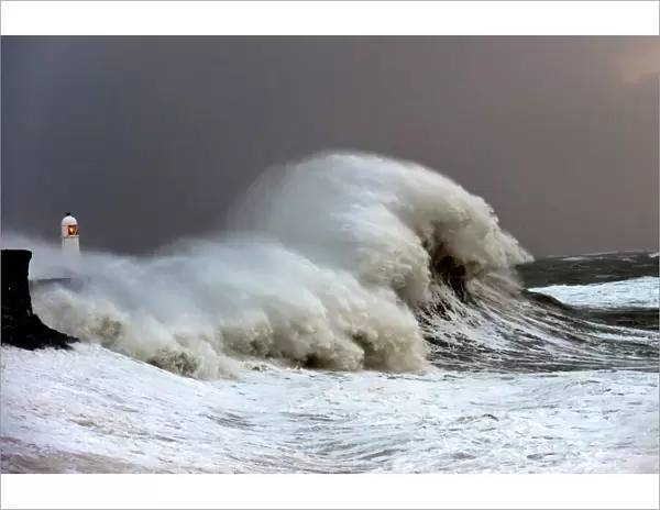 Huge waves crash against the harbour wall at Porthcawl, Bridgend, Wales, United Kingdom