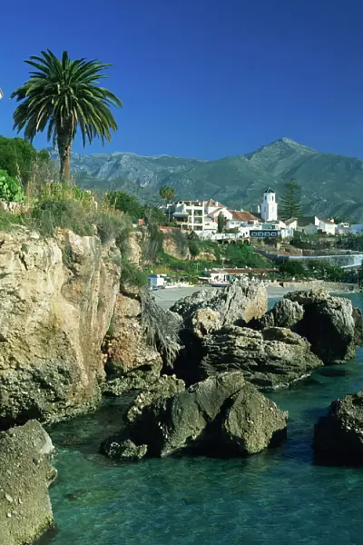 View along rocky coast to town of Nerja and mountains