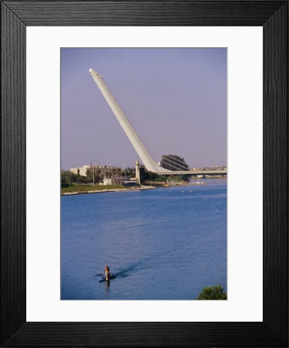 Framed Print : Man rowing with Barquetta bridge in the background Framed Print : Man rowing with Barquetta bridge in the background