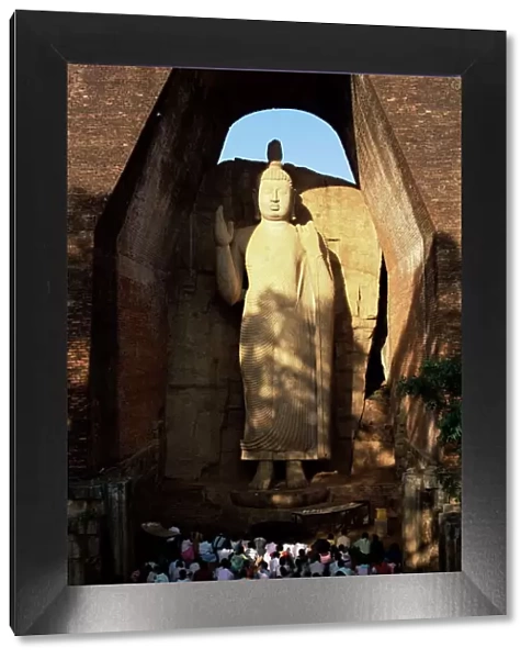 Pilgrims seated in front of the 39 ft high standing Buddha