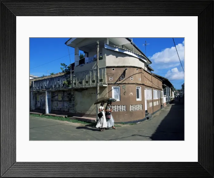 Framed Print : Young women walking round a corner on a street in Galle
