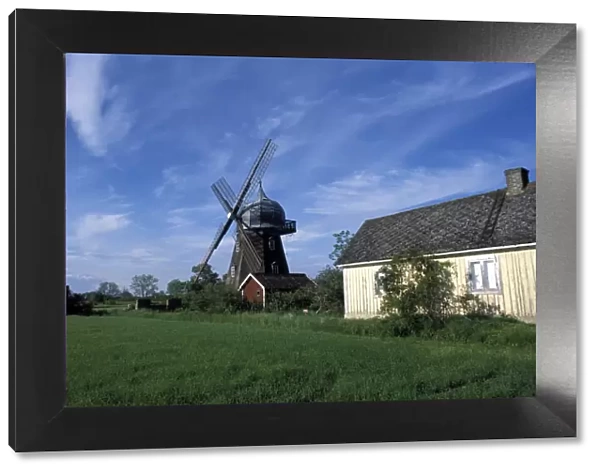 Landscape with wooden windmill and two houses in the