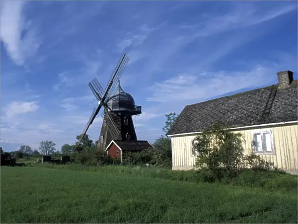 Landscape with wooden windmill and two houses in the