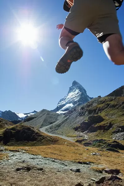Hiker running on trail and the Matterhorn