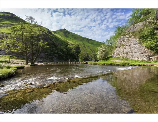 Dovedale reflections, hikers on stepping stones and Thorpe Cloud, limestone gorge in spring