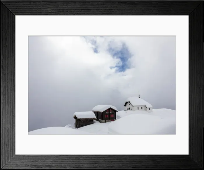Framed Print : Snow covered mountain huts and church surrounded by low clouds, Bettmeralp, district of Raron Framed Print : Snow covered mountain huts and church surrounded by low clouds, Bettmeralp, district of Raron