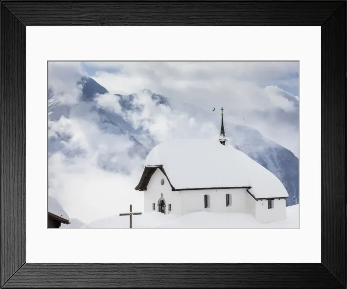 Framed Print : Clouds above the mountain huts and church covered with snow, Bettmeralp, district of Raron Framed Print : Clouds above the mountain huts and church covered with snow, Bettmeralp, district of Raron
