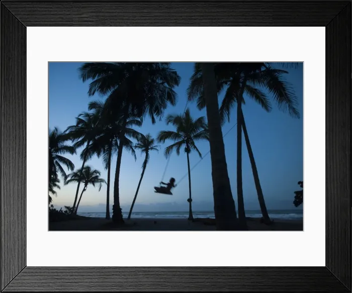 Framed Print : A girl plays on a swing tied between palm trees on the Carribean coast at Palomino in Colombia Framed Print : A girl plays on a swing tied between palm trees on the Carribean coast at Palomino in Colombia