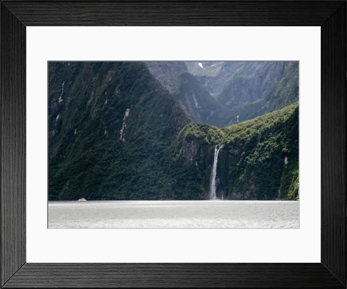 Framed Print : A sightseeing ship dwarfed by a tall waterfall in a fjord, South Island, New Zealand Framed Print : A sightseeing ship dwarfed by a tall waterfall in a fjord, South Island, New Zealand