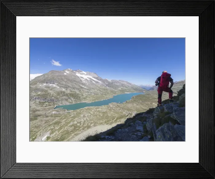 Framed Print : Hiker admires the blue alpine lake from Pizzo Campaccio, Bernina Pass, Canton of Graubunden Framed Print : Hiker admires the blue alpine lake from Pizzo Campaccio, Bernina Pass, Canton of Graubunden