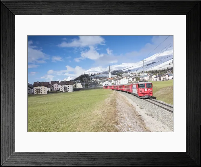 Framed Print : The red train runs across the alpine village of Zuoz in spring, Maloja, Canton of Graubunden Framed Print : The red train runs across the alpine village of Zuoz in spring, Maloja, Canton of Graubunden