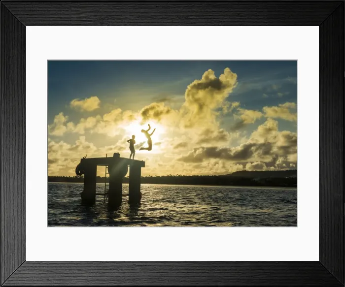 Framed Print : Backlit local boys jumping into the water of the lagoon of Wallis from a platform Framed Print : Backlit local boys jumping into the water of the lagoon of Wallis from a platform