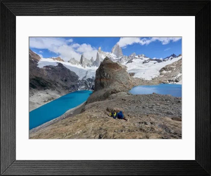 Framed Print : A couple in mountain gear rests on rocks with view to Lago de los Tres and Mount Fitz Roy Framed Print : A couple in mountain gear rests on rocks with view to Lago de los Tres and Mount Fitz Roy