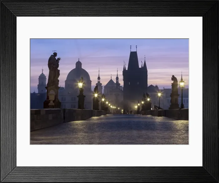 Framed Print : Street lanterns and old statues frame the historical buildings on Charles Bridge at dawn Framed Print : Street lanterns and old statues frame the historical buildings on Charles Bridge at dawn