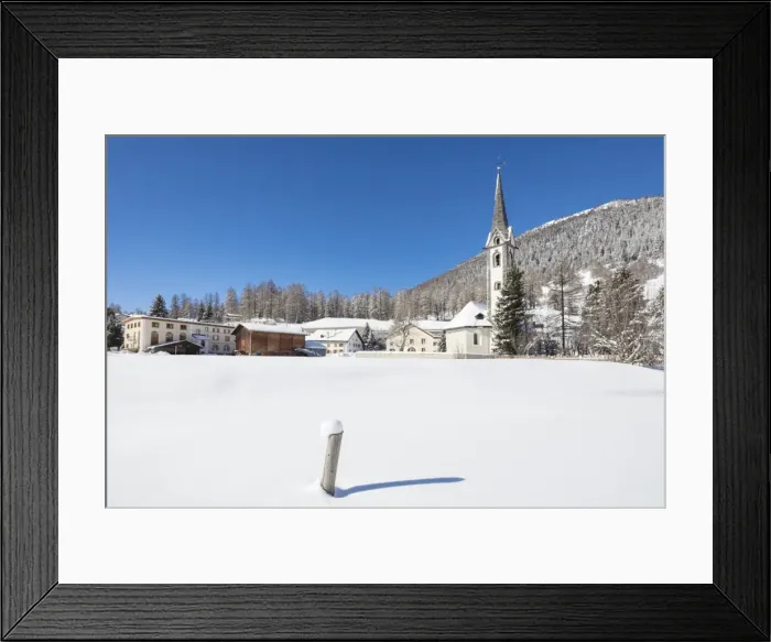 Framed Print : The alpine village covered with snow framed by blue sky, Cinuos, Canton of Graubunden