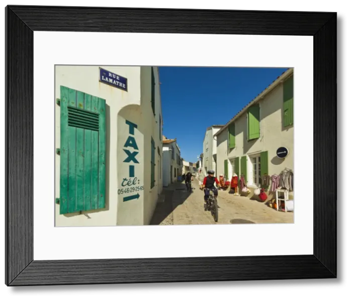 Framed Print : Cyclist on Rue Lamathe in the islands principal western town, Ars en Re, Ile de Re Framed Print : Cyclist on Rue Lamathe in the islands principal western town, Ars en Re, Ile de Re