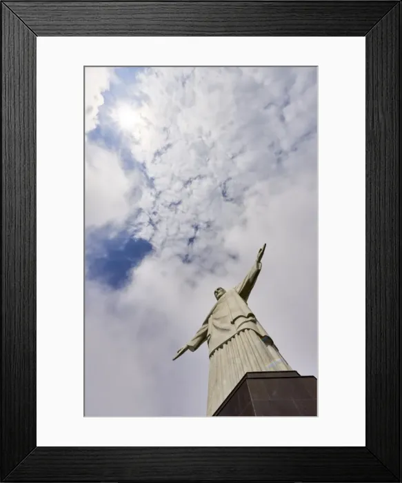 Framed Print : Low angle shot of the iconic statue of Christ the Redeemer on a cloudy day with sun Framed Print : Low angle shot of the iconic statue of Christ the Redeemer on a cloudy day with sun