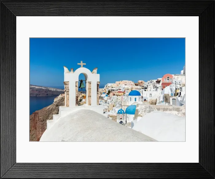 Framed Print : A church roof and bell with the white washed stone walls and blue church cupolas of Oia Framed Print : A church roof and bell with the white washed stone walls and blue church cupolas of Oia