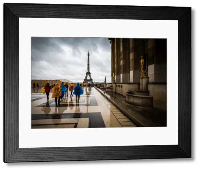 Framed Print : Heading towards the Eiffel Tower, tourists brave the rain in colourful ponchos Framed Print : Heading towards the Eiffel Tower, tourists brave the rain in colourful ponchos