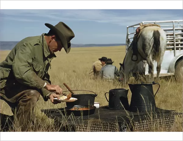 Cowboys eating breakfast in a field