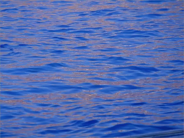 Ripples in water reflecting light and blue sky
