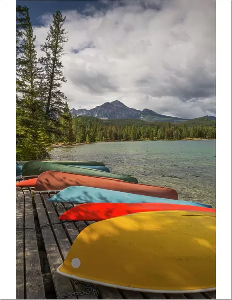 Colourful canoes and kayaks on the bank of Annette Lake with Pyramid Mountain in the background