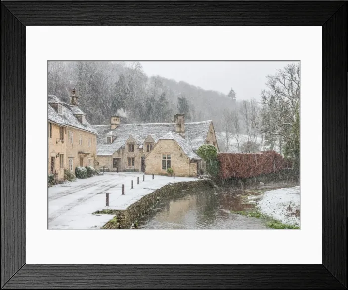 Framed Print : Snow covered houses by By Brook in Castle Combe with a dog enjoying a paddle, Wiltshire Framed Print : Snow covered houses by By Brook in Castle Combe with a dog enjoying a paddle, Wiltshire