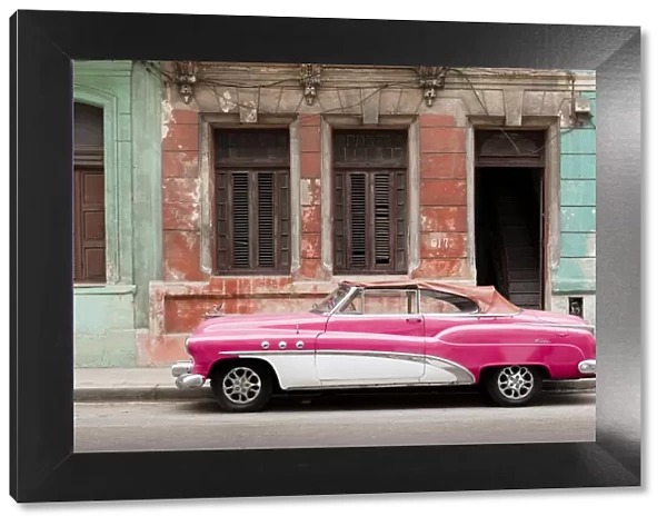 A pink and white vintage American convertible car parked on a street in Havana, Cuba