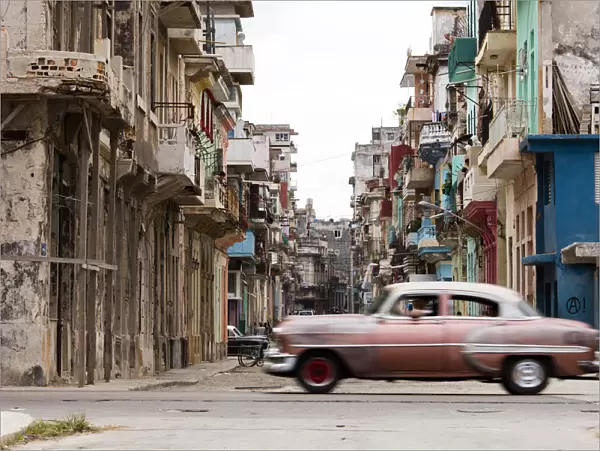 A vintage American car driving across a street in Havana, Cuba, West Indies, Caribbean