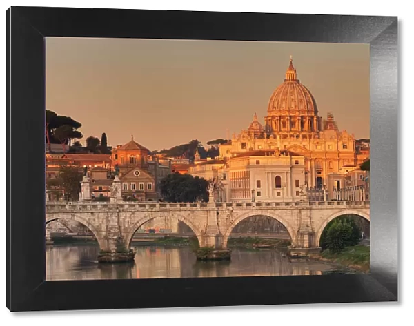View over Tiber River to Ponte Vittorio Emanuele II Bridge and St. Peters Basilica at sunrise
