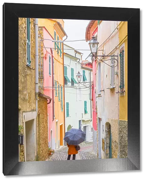 A person with an umbrella in the main street of Civezza, Province of Imperia, Liguria