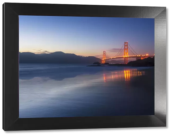 Soft flowing water reflects the beautiful Golden Gate Bridge from Baker Beach, San Francisco