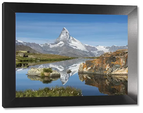 A walker hiking in the Alps takes in the view of the Matterhorn reflected in Stellisee