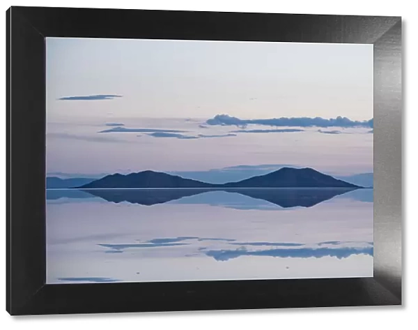 Pastel-coloured beauty of salt flats reflecting the clouds and mountains after rainfall