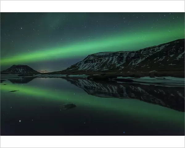 Aurora borealis (Northern Lights) reflected in partially frozen lake, North Snaefellsnes