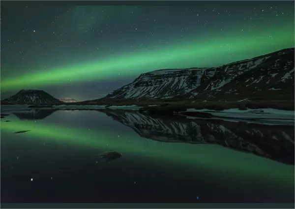 Aurora borealis (Northern Lights) reflected in partially frozen lake, North Snaefellsnes