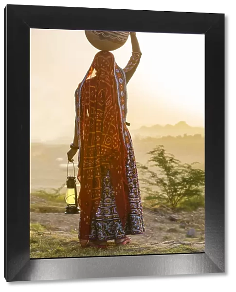 Ahir Woman in traditional colorful cloth carrying water in a clay jug on her head